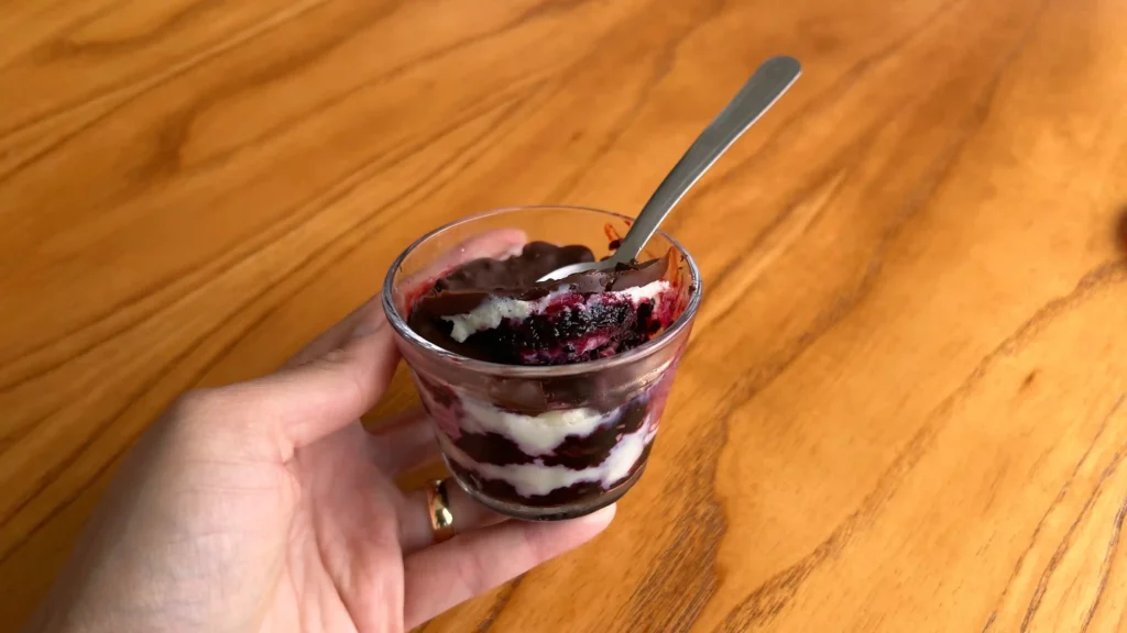 Mão segurando bombom de pote na mesa com uma colher mergulhada na receita